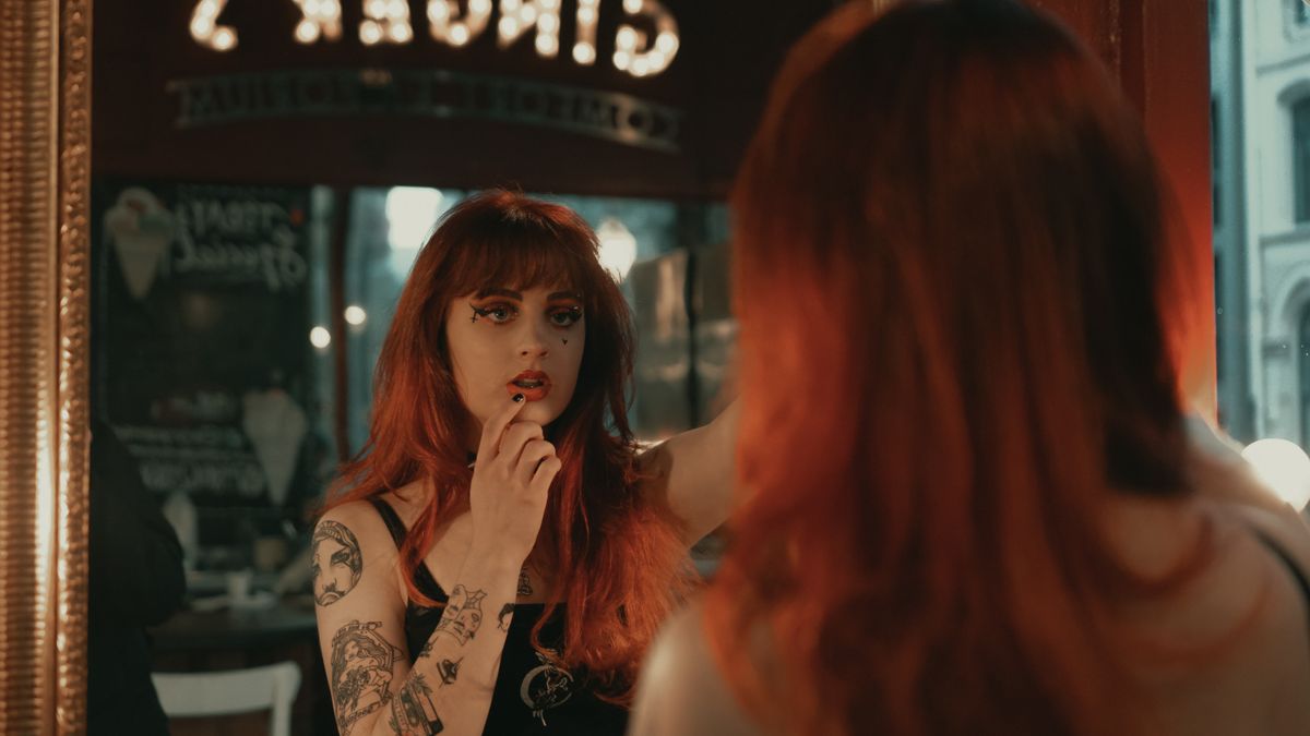 Stock photo: a woman with red hair touches her lip in a café mirror, warm light